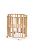 Stokke mini oval crib with natural finish, adjustable height, and wheels (British brand)